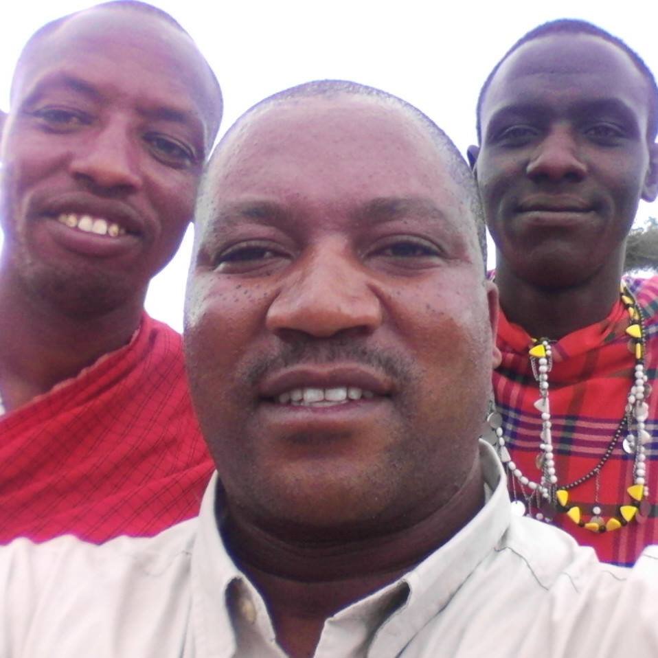 Ambrose Mtui taking a selfie with two men in traditional Maasai dress