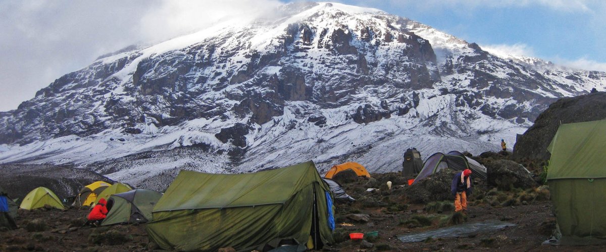 Tents at a high camp below the snow-covered summit of Kilimanjaro