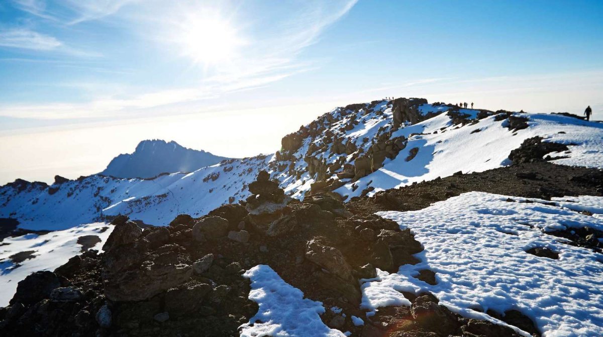 Climbers on a snowy ridge high on Kilimanjaro under a bright sun